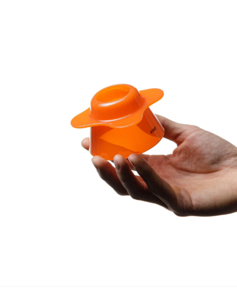 Hand holding an orange plastic funnel device